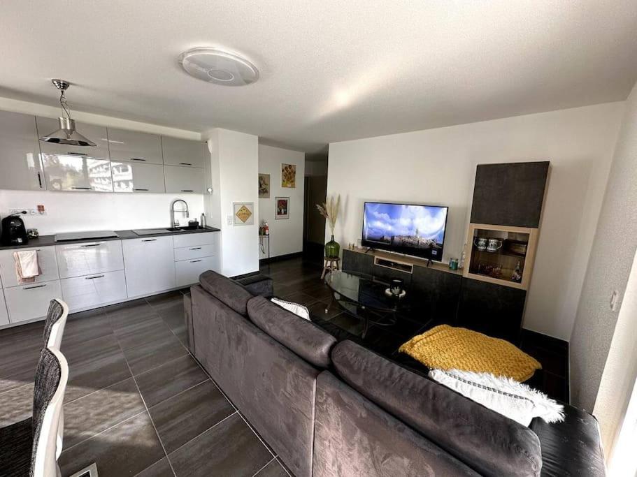 salon z brązową kanapą i kuchnią w obiekcie Superbe appartement proche de Strasbourg w mieście Bischheim