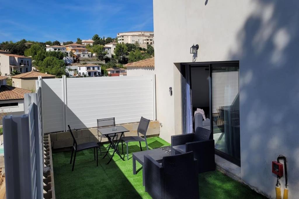 patio ze stołem i krzesłami na trawie w obiekcie logement indépendant avec terrasse "Les Mésanges" w mieście Juvignac
