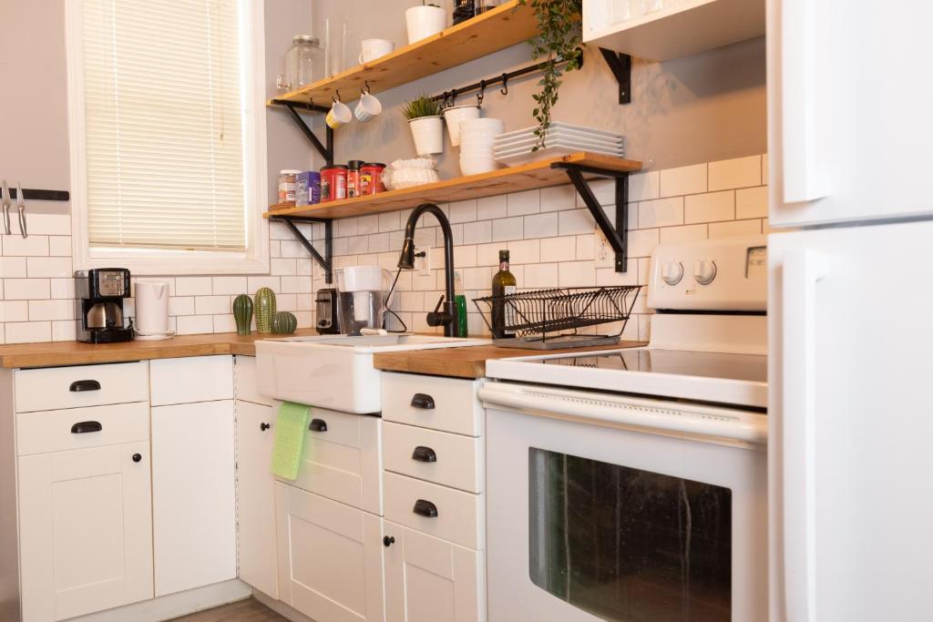 Cozy Home in Downtown Winnipeg في وينيبيغ: مطبخ بدولاب أبيض وأجهزة بيضاء