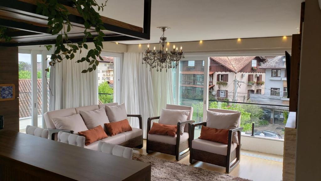 - un salon avec une table, des chaises et une grande fenêtre dans l'établissement Apto Centro Gramado, à Gramado