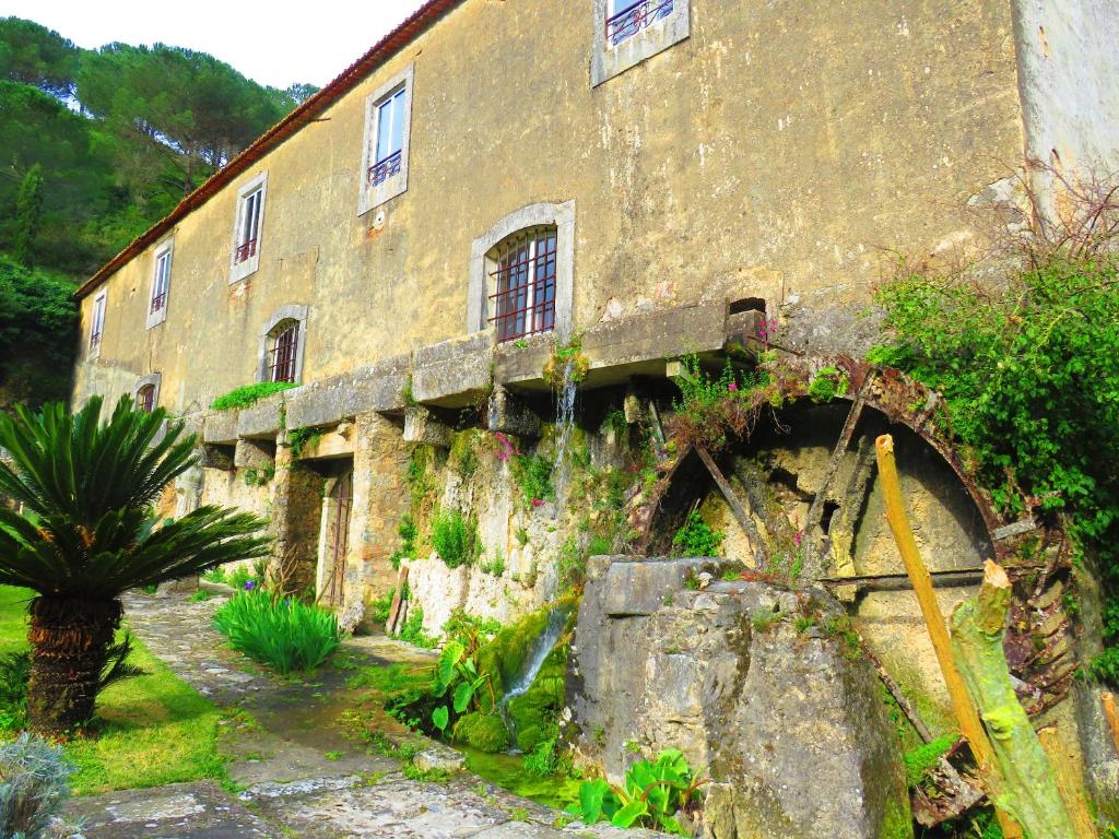ein altes Steingebäude mit einer Palme davor in der Unterkunft One bedroom house with lake view shared pool and furnished garden at Porto de Mos in Porto de Mós