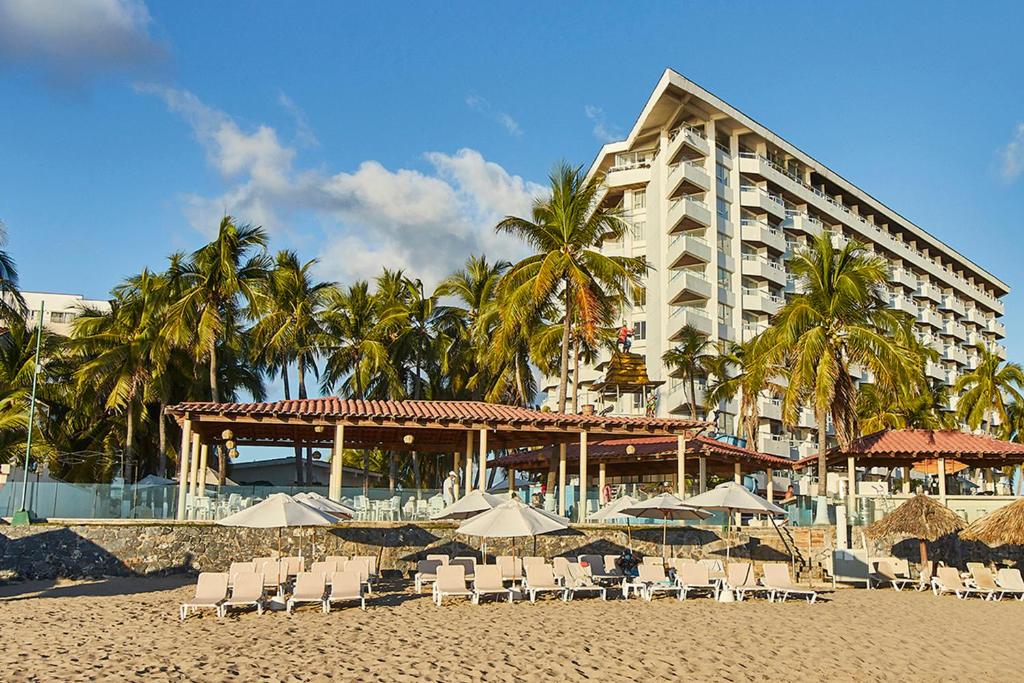 un hotel sulla spiaggia con sedie e ombrelloni di Krystal Ixtapa a Ixtapa