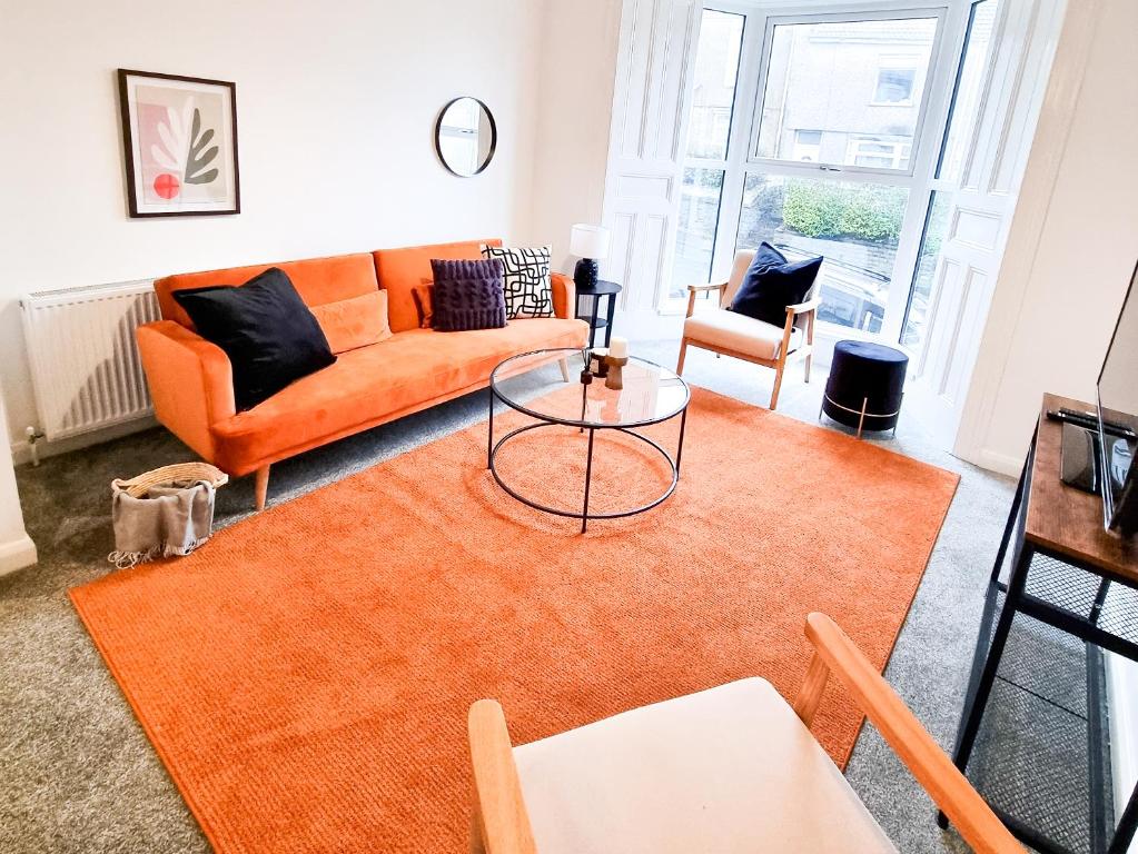 a living room with an orange couch and a table at Spacious 3-bed near the city centre in Swansea