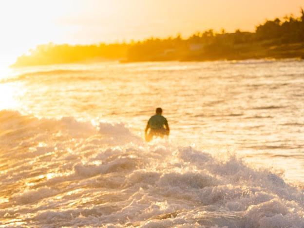a man walking into the water in the ocean at OceanBlue Resort in Christ Church