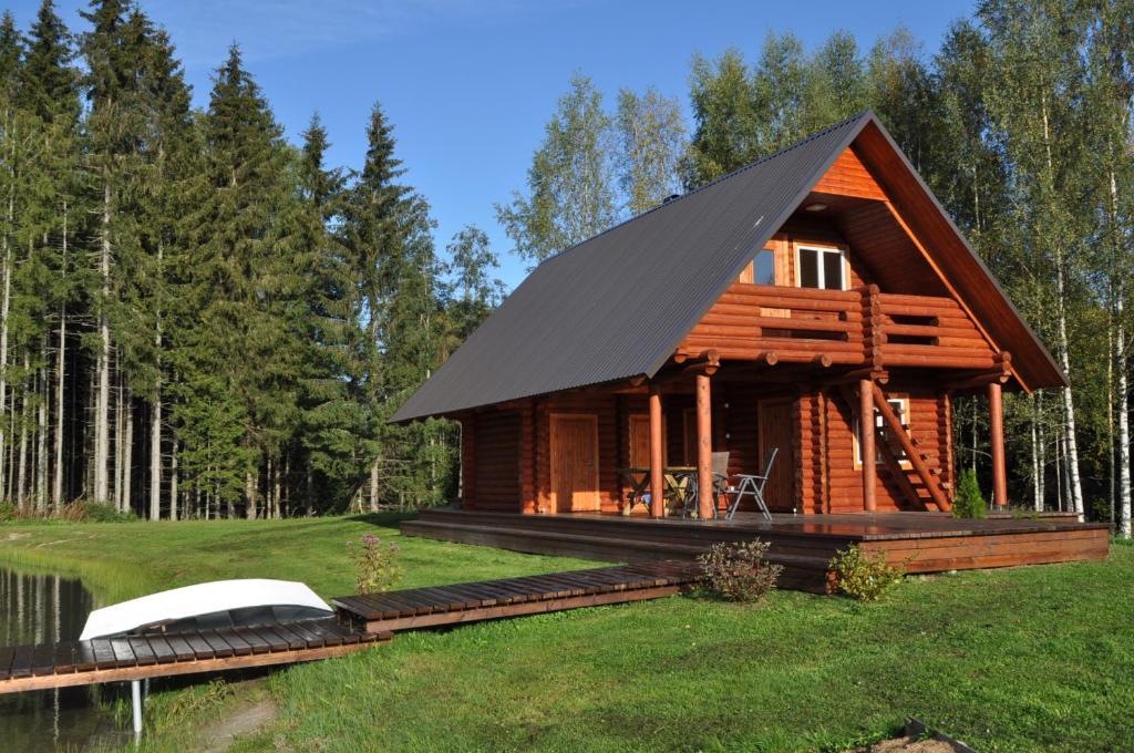 a cabin in the woods with a black roof at Suurepera puhkekeskuse saunamaja 