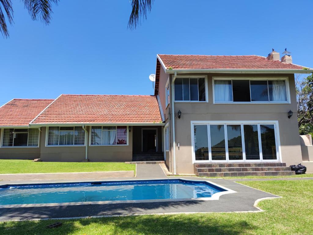 a house with a swimming pool in front of it at Peace of Mind Holiday Home in Amanzimtoti