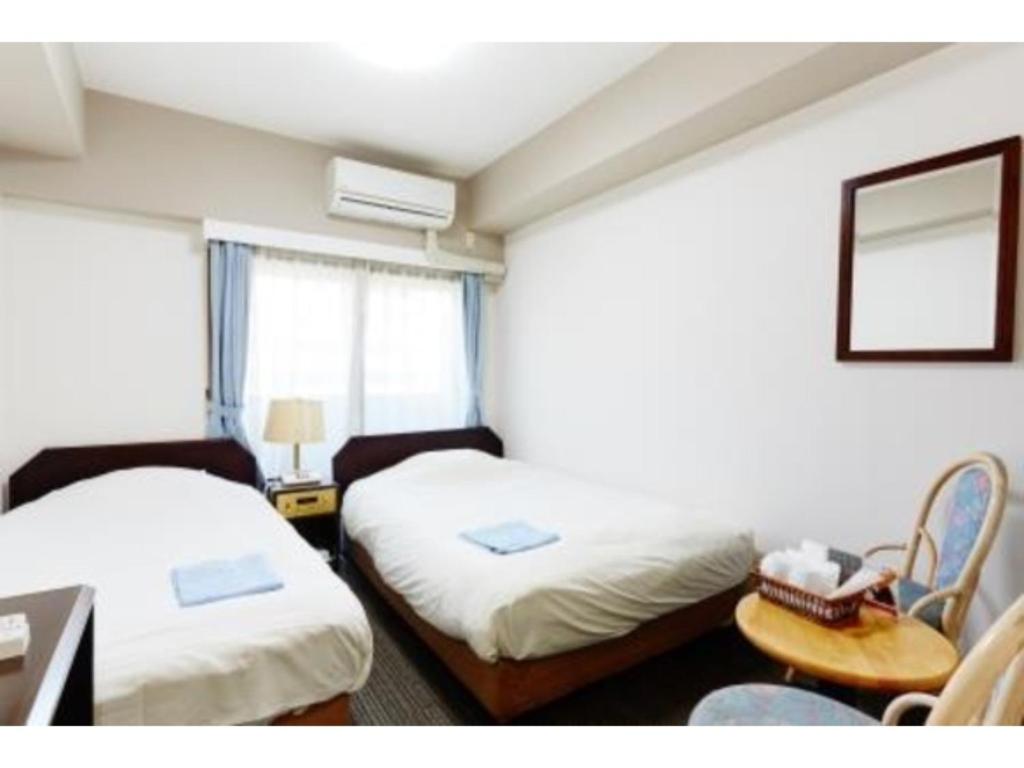 東京にあるHotel Business Villa Omori - Vacation STAY 08221vのベッド2台、デスク、テーブルが備わる客室です。