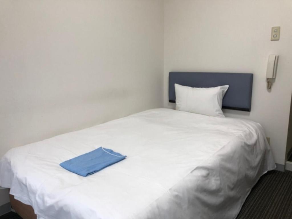 Una cama blanca con una carpeta azul encima. en Hotel Business Villa Omori - Vacation STAY 08185v, en Tokio