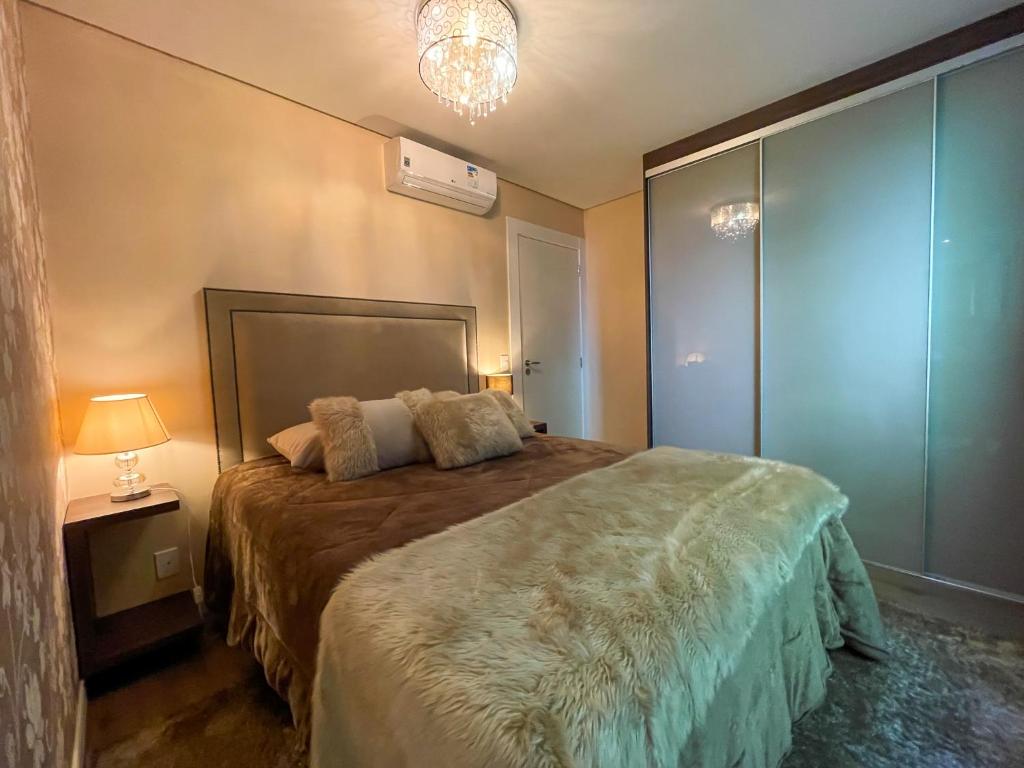 1 dormitorio con 1 cama grande y 1 lámpara en Apto Luxo Centro Gramado en Gramado