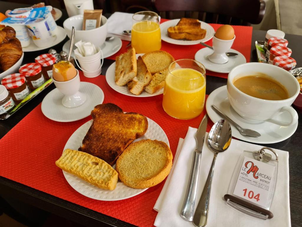 un tavolo con colazione a base di pane tostato, caffè e succo d'arancia di Hôtel Bistrot Le Marceau a Limoges