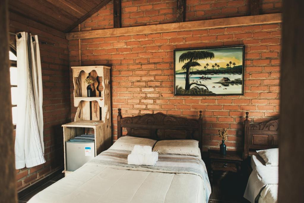 ein Schlafzimmer mit einem Bett in einer Ziegelwand in der Unterkunft Chalés Vida Verde in Bom Jardim de Minas