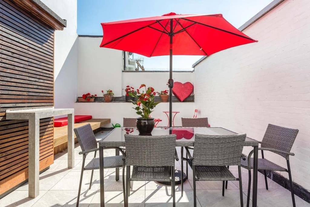 un patio con una mesa con una sombrilla roja en Roof garden house, en Brighton & Hove