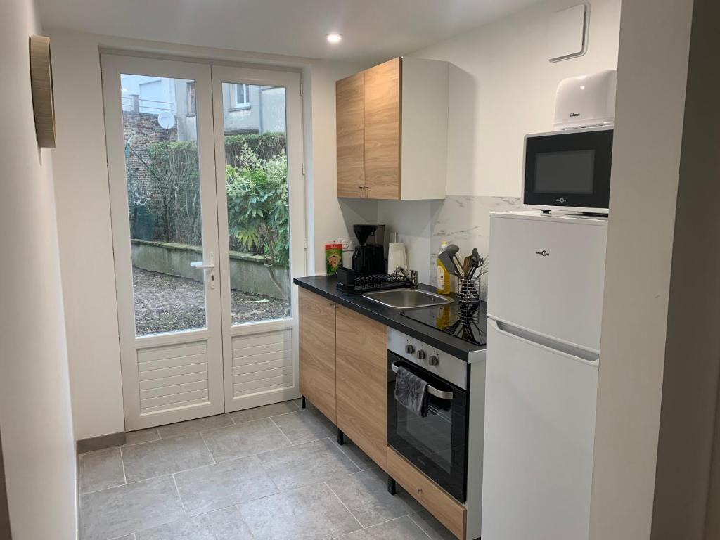 a kitchen with a white refrigerator and a sink at Bel appartement neuf avec jardin, proche mer in Calais