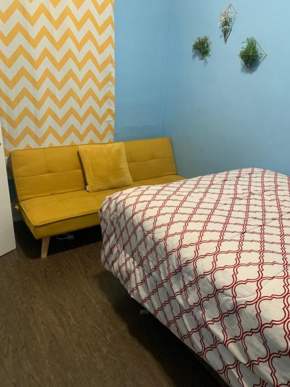 a bedroom with a bed and a yellow couch at Niagara Getaway in Niagara Falls