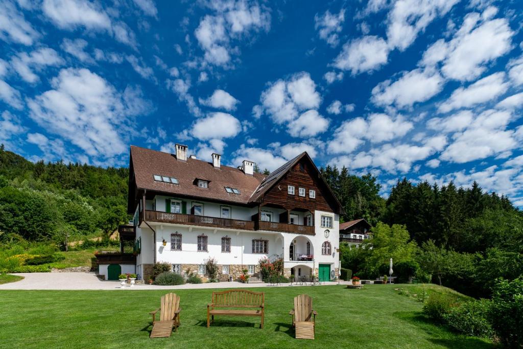 a large house with two benches in the yard at Villa Weiss in Attersee am Attersee