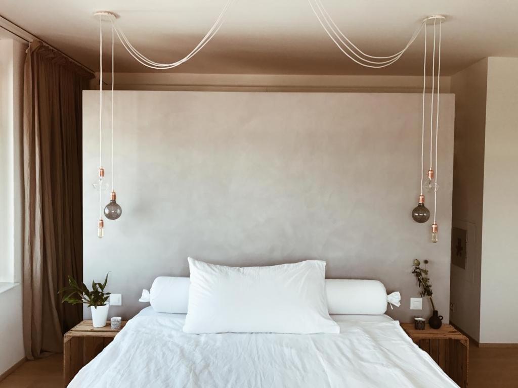 a bedroom with a bed with white sheets and lights at AVLiving City INSIDE NINE Basel in Basel