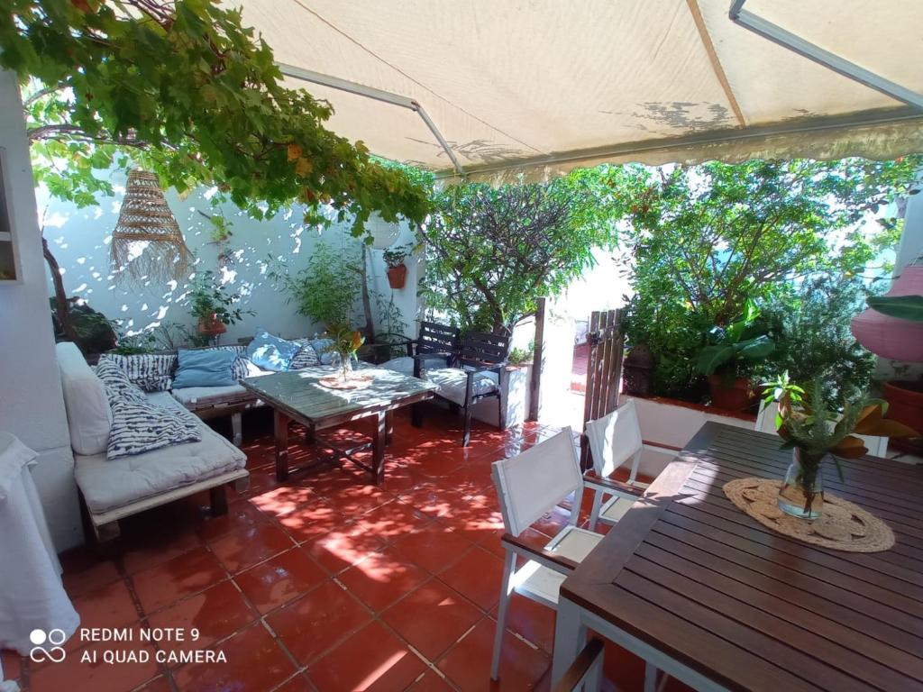 un patio al aire libre con mesa, sillas y árboles en Pareado en Loma Sancti Petri a 900 m de la playa de La Barrosa en Chiclana de la Frontera