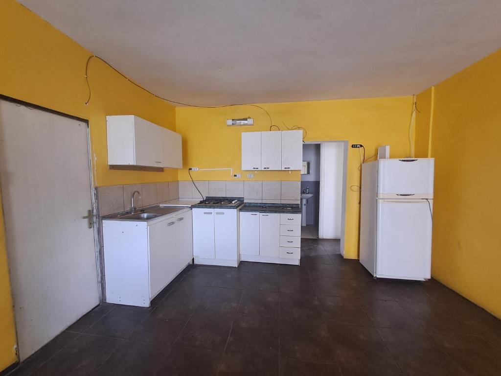 una cocina vacía con electrodomésticos blancos y paredes amarillas en Casa forestal, en Viña del Mar