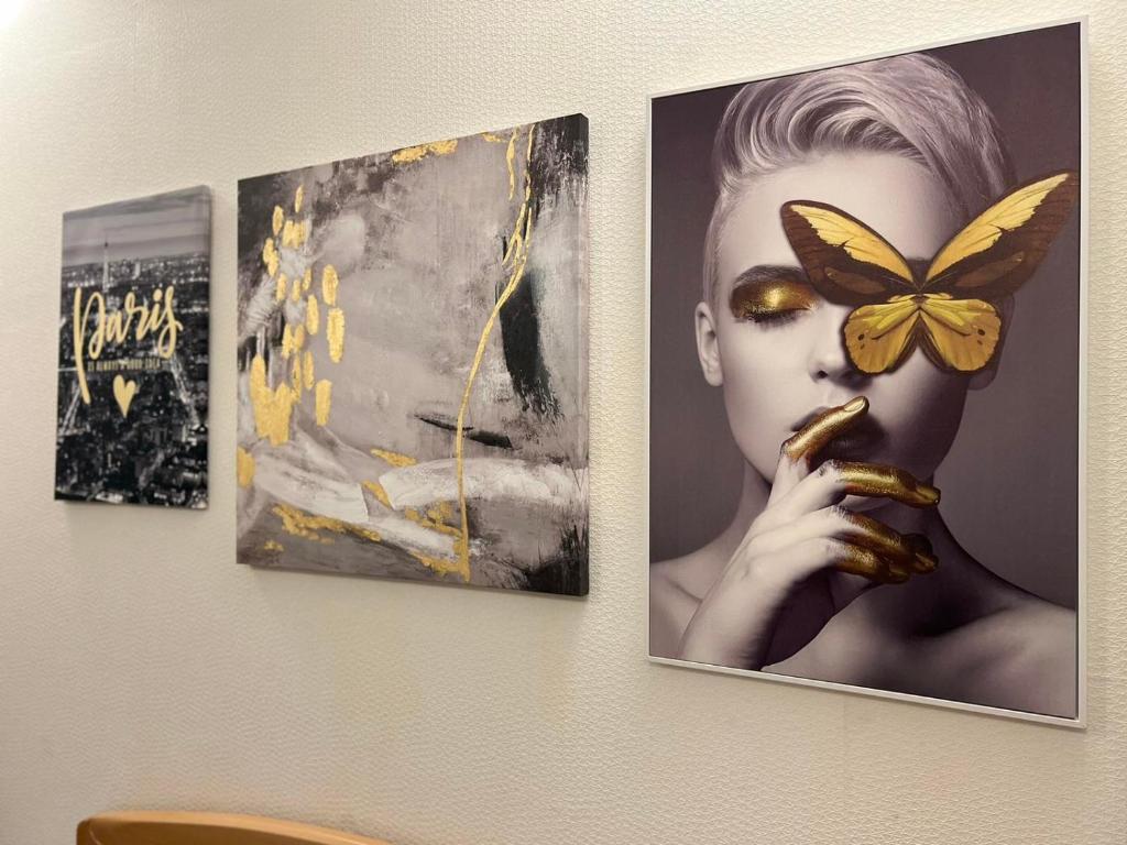 three pictures of a woman with a butterfly on a wall at Cute little apartment in Belgrade