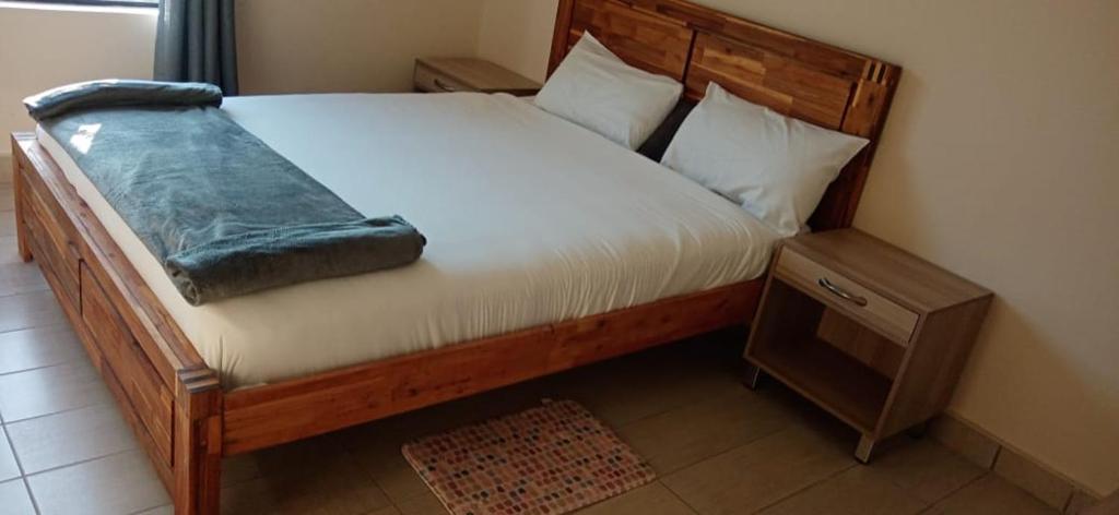 Bett mit einem Kopfteil aus Holz und einem Nachttisch in der Unterkunft Hlalakahle Lodge in Glencoe