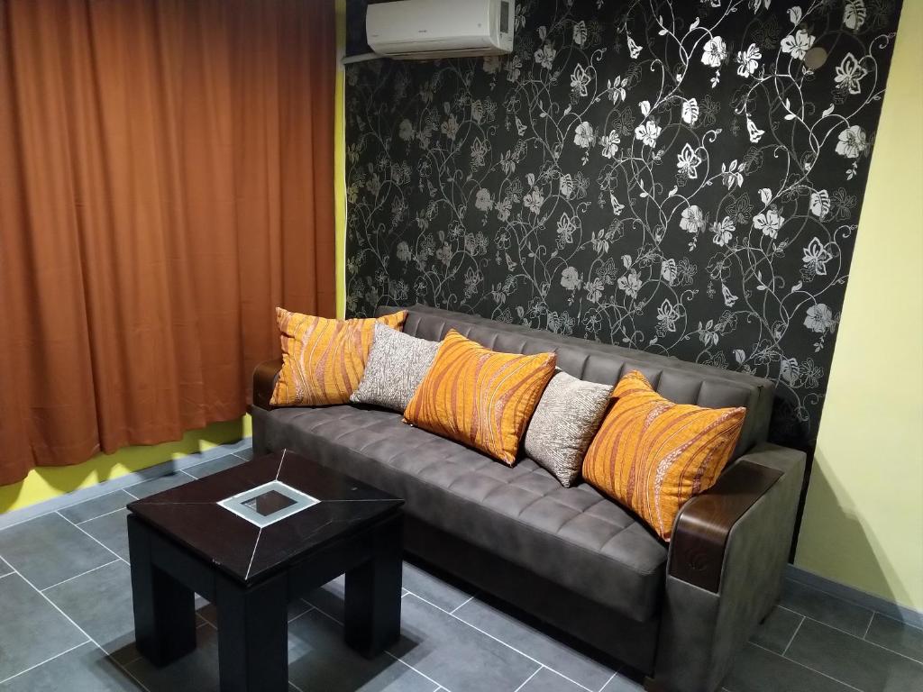 ein braunes Sofa mit orangefarbenen Kissen im Wohnzimmer in der Unterkunft Eli Apartment in Burgas City