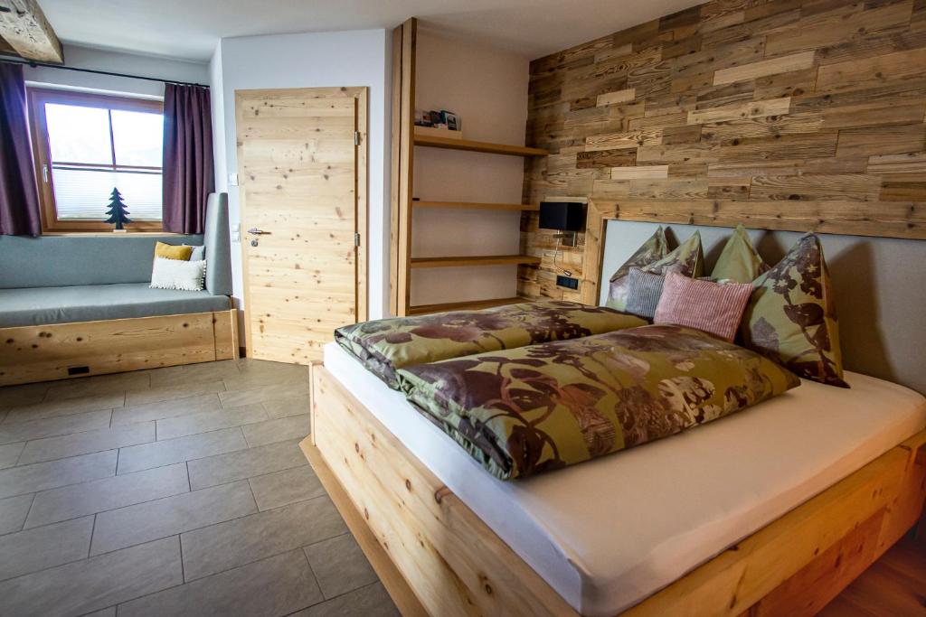 1 dormitorio con 1 cama con pared de madera en Apartment LENA, en Obertilliach