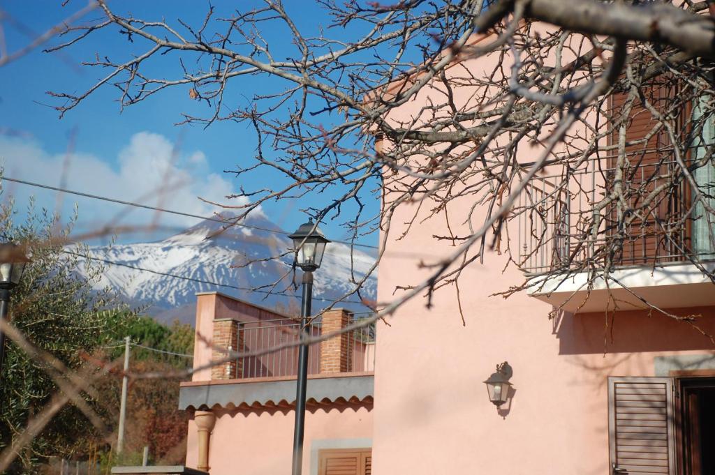 um edifício cor-de-rosa com uma luz de rua e uma montanha ao fundo em Casa Farlazzo em Zafferana Etnea