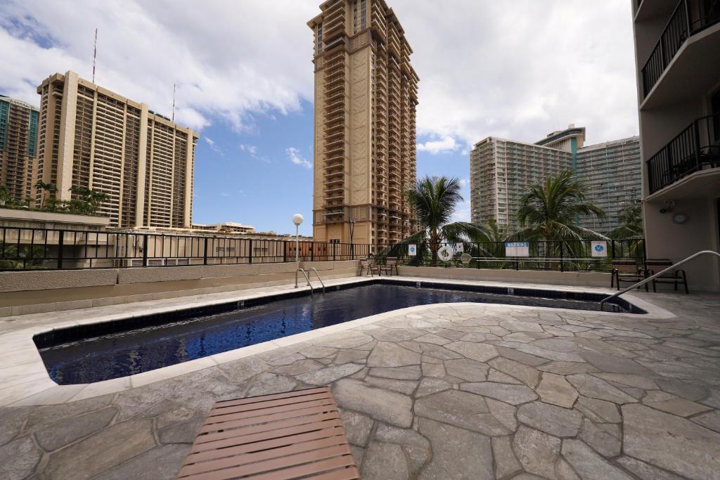 a swimming pool in the middle of a city with tall buildings at Apartments at Palms Waikiki in Honolulu