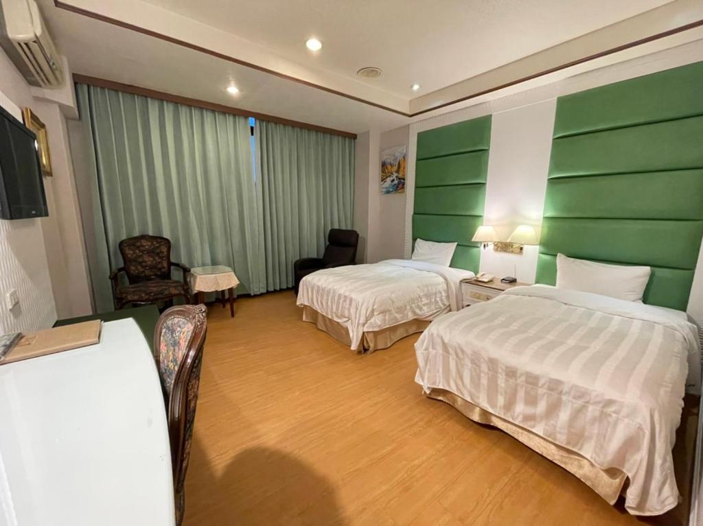 a hotel room with two beds and green walls at Wenpin Hotel - Pier 2 in Kaohsiung