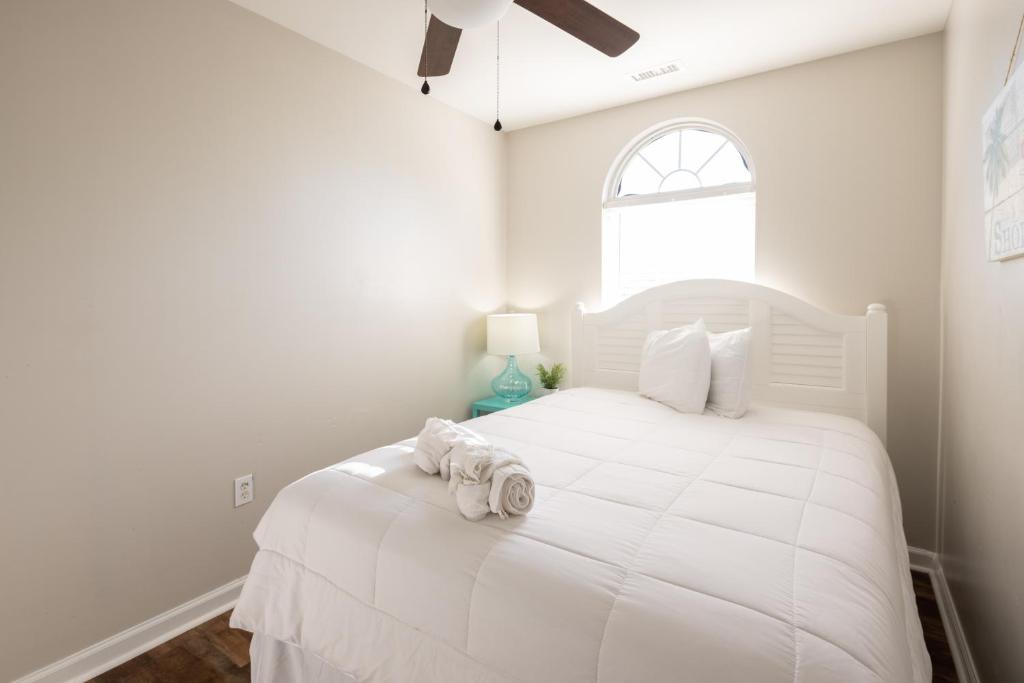 a white bedroom with a large white bed with a window at Coquina Casita in Myrtle Beach