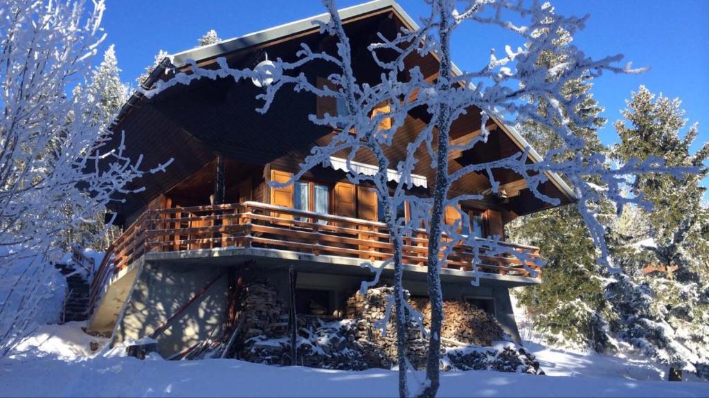 a log cabin in the snow with snow covered trees at Chalet Les Airelles in Montcel