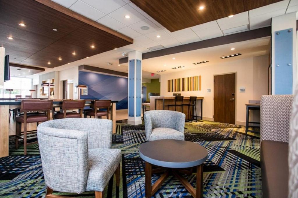a waiting room with chairs and a table and a bar at Holiday Inn Express & Suites Rehoboth Beach, an IHG Hotel in Rehoboth Beach