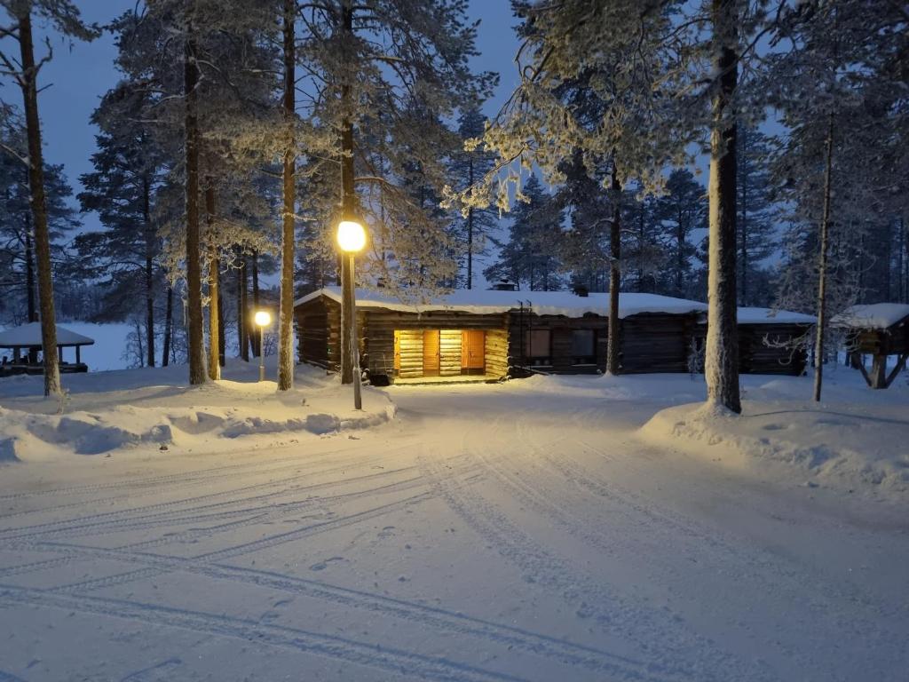 a cabin in the woods in the snow at night at Villa Uuttu in Kuusamo