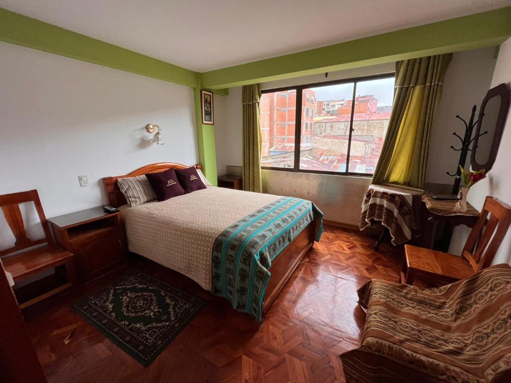 1 dormitorio con cama, ventana y silla en Hostal Iskanwaya, en La Paz