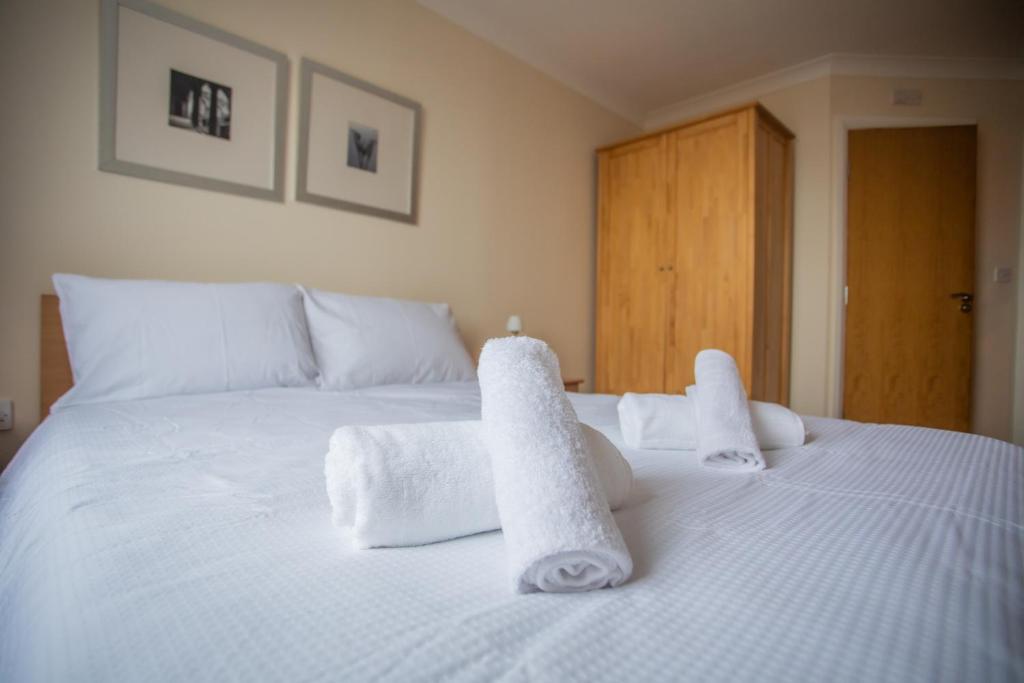 Una cama blanca con toallas encima. en Cosy 2 bed flat near train station Basingstoke with FREE Parking!, en Basingstoke