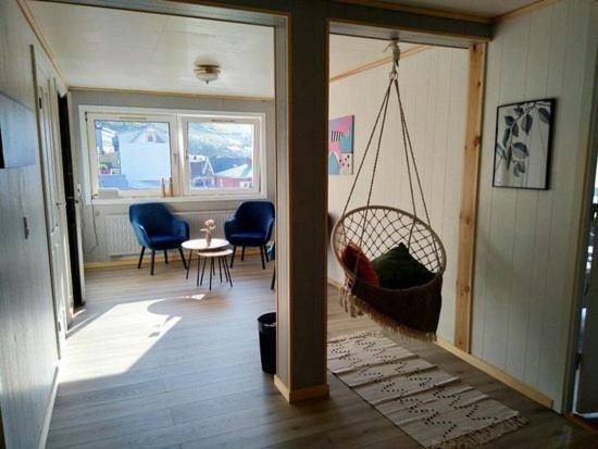 uma sala de estar com um baloiço, uma mesa e cadeiras em Kassie & Gia's Home em Vestnanhavn