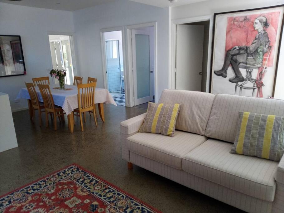 een woonkamer met een witte bank en een tafel met stoelen bij The Artist's Cottage in Bendigo
