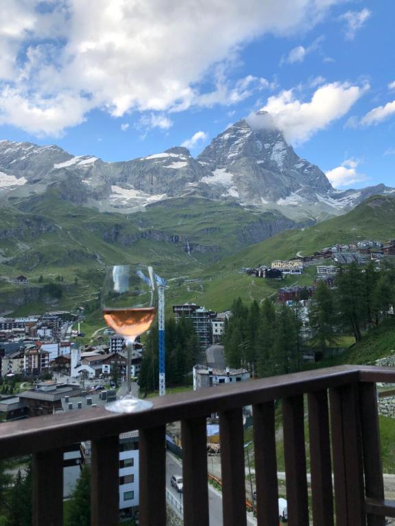 a glass of wine on a balcony with a mountain at Eagle's Nest in Breuil-Cervinia
