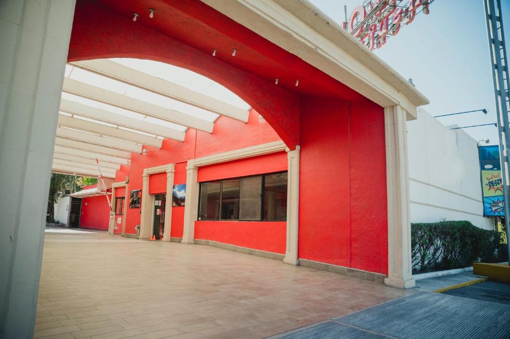 ein rotes Gebäude mit einem Torbogen auf der Seite in der Unterkunft Hotel La Fuente, Saltillo in Saltillo