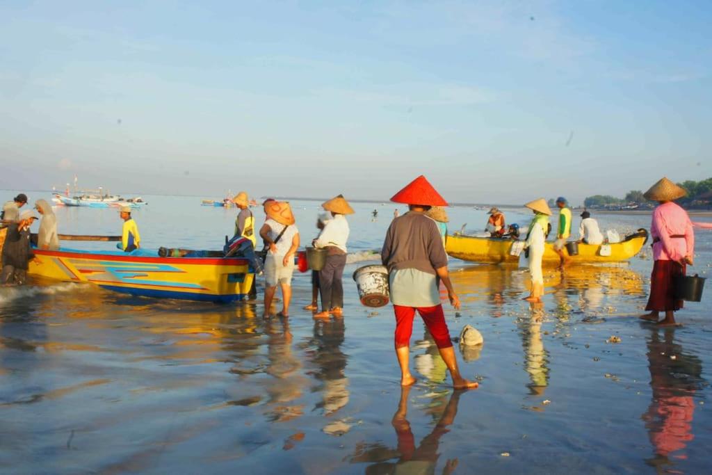 ジンバランにあるマンゴ ツリー ヴィラズの海岸に船を乗せた人々