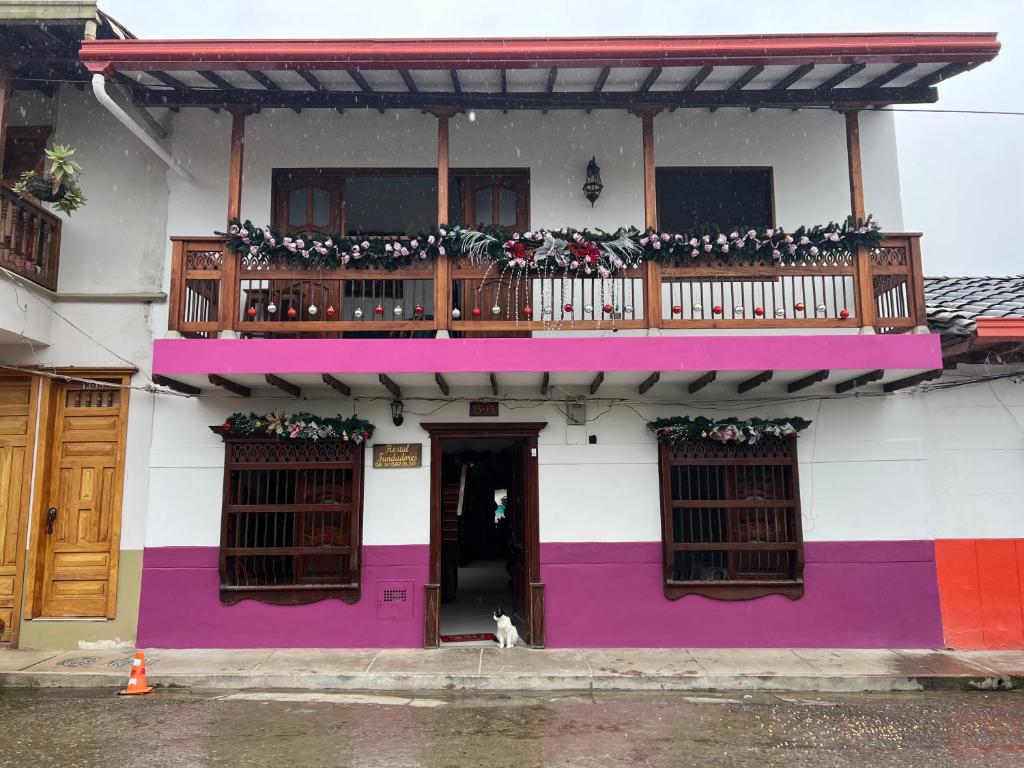 a colorful building with a balcony and a dog sitting in front at Hostal Famihotel Fundadores in Jardin