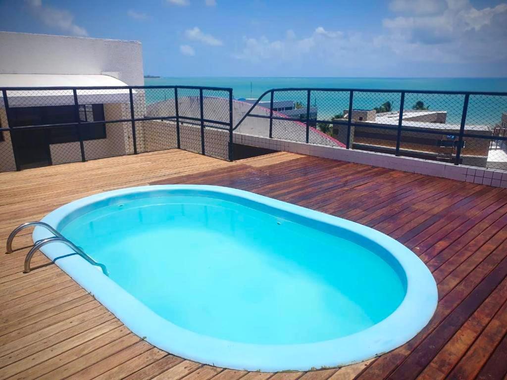una gran bañera azul en una terraza con la playa en Bessa Beach Inn Ideal para Famílias, en João Pessoa