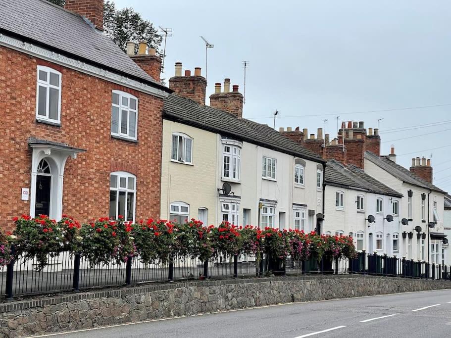 a row of houses with red flowers on a street at Beautiful, 1 Bedroom Renovated Cottage in Leicester