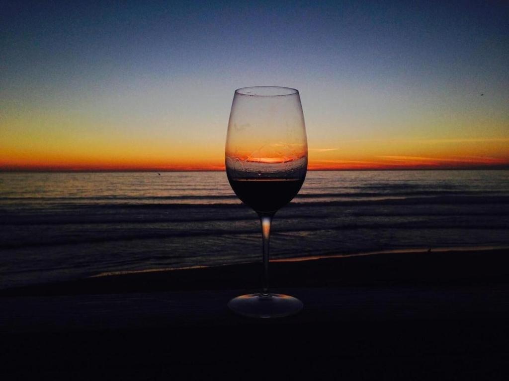 a glass of wine sitting on the beach at sunset at Ocean Front Getaway in La Selva Beach in La Selva Beach