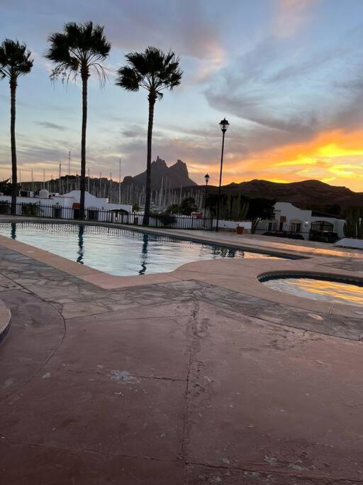 a swimming pool with palm trees and a sunset at Casa Villa Serena in San Carlos
