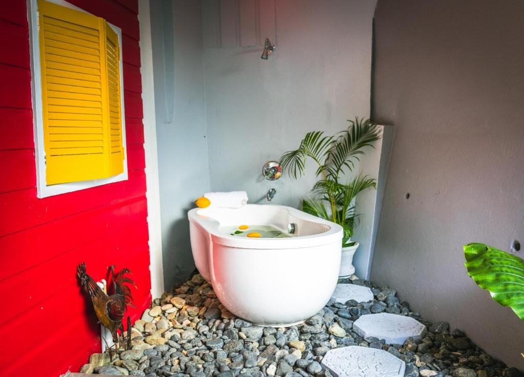 a bathroom with a bath tub next to a red door at Castara Cottage by Hello Mello in Castara