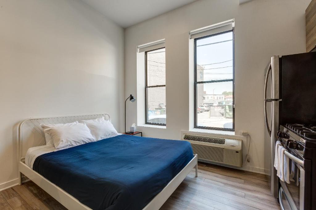 a bedroom with a bed with blue sheets and two windows at Ground Floor Studios in Chicago by 747 Lofts in Chicago