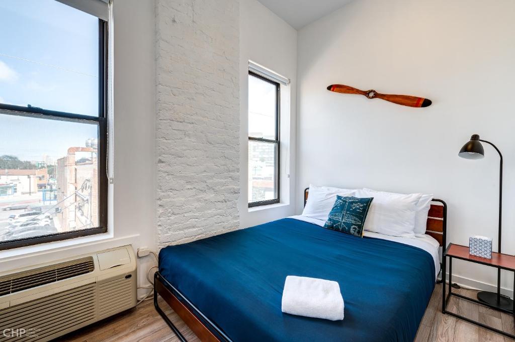 een slaapkamer met een blauw bed en 2 ramen bij Chicago Third Floor Studio by 747 Lofts in Chicago