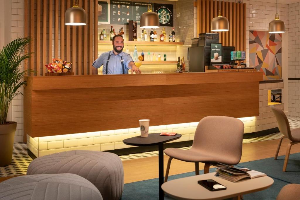 un homme debout derrière le comptoir d'un restaurant dans l'établissement Holiday Inn Express - Marne-la-Vallée Val d'Europe by IHG, à Bailly-Romainvilliers