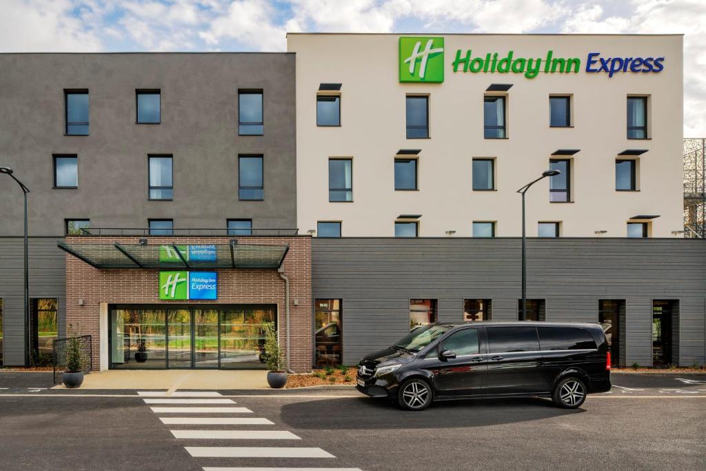Holiday Inn Express - Marne-la-Vallée Val d'Europe, an IHG Hotel في بايلي رومانفيل: سيارة فان سوداء متوقفة أمام الفندق